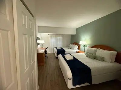 a hotel room with two beds and a desk at SkySuite 5min to Universal Park in Orlando