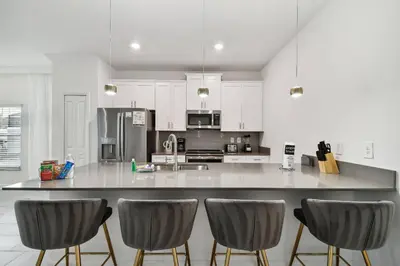 a kitchen with a large counter with chairs in it at Casa Disney | Piscina Privativa no Storey Lake in Kissimmee