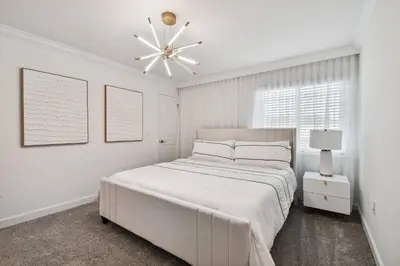 a white bedroom with a large bed and a chandelier at Casa Disney | Piscina Privativa no Storey Lake in Kissimmee