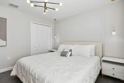 a white bedroom with a large bed and a chandelier at Casa Disney | Piscina Privativa no Storey Lake in Kissimmee