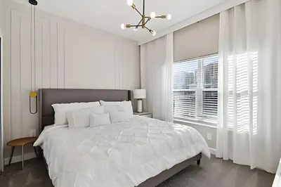 a white bedroom with a large bed and a window at Casa Disney | Piscina Privativa no Storey Lake in Kissimmee