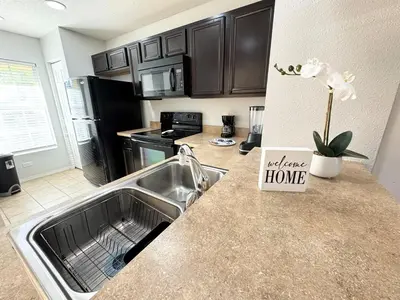 a kitchen with a sink and a counter with a welcome home sign at 2BR Villa Near Disney, Gated community with Pool in Kissimmee