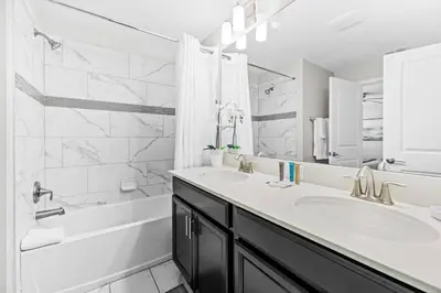 a white bathroom with a tub and a sink and a bath tubermott at Casa Familiar no Storey Lake c/ Piscina in Kissimmee