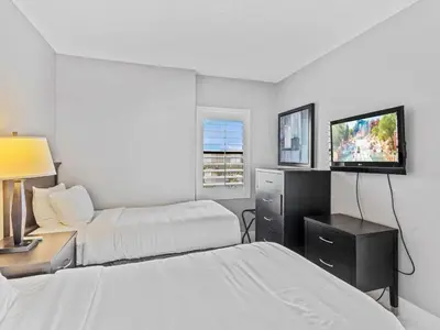 a hotel room with two beds and a flat screen tv at Apartamento Aconchegante no Enclave Suites in Orlando