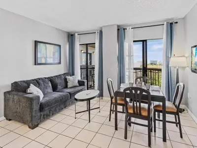 a living room with a couch and a table and chairs at Apartamento Aconchegante no Enclave Suites in Orlando