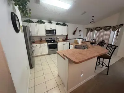 a kitchen with a refrigerator and a counter top at Cumbrian Sunset Villa home in Kissimmee