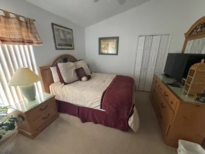 a bedroom with a bed and a dresser with a television at Cumbrian Sunset Villa home in Kissimmee