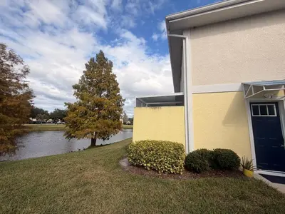 a house with a tree next to a body of water at Royal Homes in Kissimmee