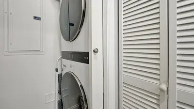 a mirror hanging on a wall next to a washing machine at Wands & Wishes | Luxury Condo Minutes from Disney in Orlando
