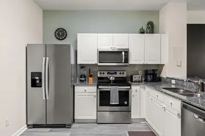 a kitchen with white cabinets and a stainless steel refrigerator at Magical Stay Near Disney I Pool and Resort Access in Kissimmee