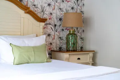 a bed with a green pillow and a lamp on a night stand at Magical Stay Near Disney I Pool and Resort Access in Kissimmee