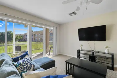 a living room with a couch and a flat screen tv at Spacious 2BR Condo Near Disney with Pool & Basketball in Kissimmee