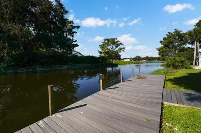 a wooden dock on a river with trees and water at Spacious 2BR Condo Near Disney with Pool & Basketball in Kissimmee