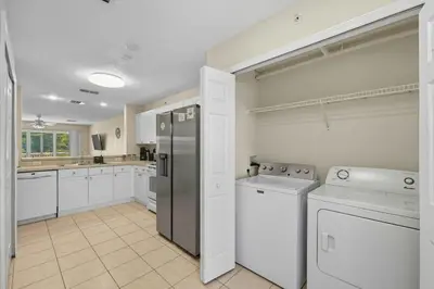a kitchen with white cabinets and a stainless steel refrigerator at Spacious 2BR Condo Near Disney with Pool & Basketball in Kissimmee