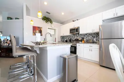 a kitchen with white cabinets and a stainless steel refrigerator at Game Room 4 BD Private Pool BBQ 2252 in Kissimmee