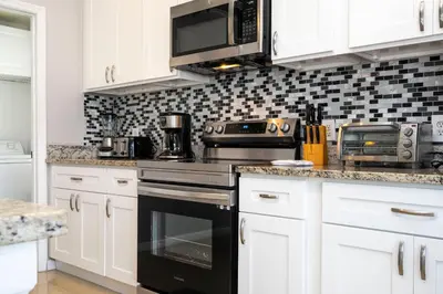 a kitchen with white cabinets and a black oven at Game Room 4 BD Private Pool BBQ 2252 in Kissimmee