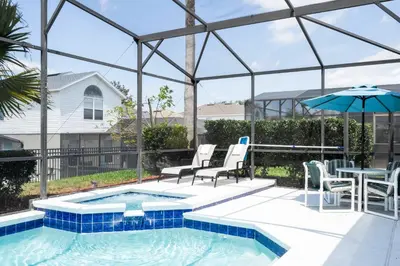 a swimming pool with chairs and a table and an umbrella at Game Room 4 BD Private Pool BBQ 2252 in Kissimmee