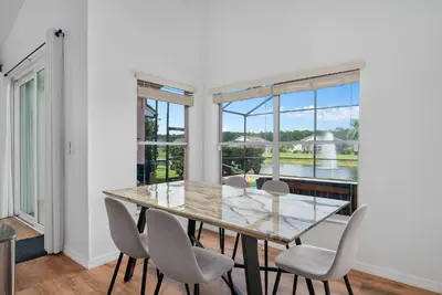 a dining room with a table and chairs and windows at [Popular Illusion Home] •Waterfront Private Pool in Kissimmee