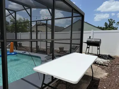 a pavilion with a white table and a chair next to a pool at 3 bedroom home with private pool in Orlando