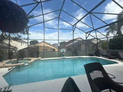 a swimming pool with two chairs and a glass roof at Cozy family house near Disney,epic and universal in Orlando
