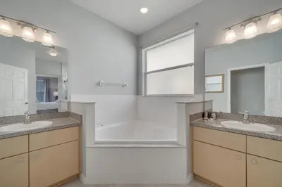 a bathroom with two sinks and a tub and a window at Disney Getaway Pool Gated Resort Near Parks in Kissimmee