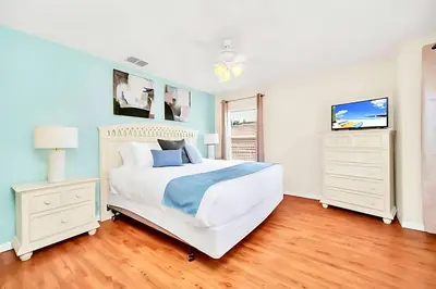 a white bedroom with a bed and a tv at Bella Vida House with Pool and Games - Near Disney! in Kissimmee