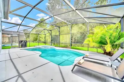an indoor pool in a glass house with a swimming pool at Bella Vida House with Pool and Games - Near Disney! in Kissimmee