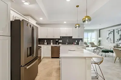 a kitchen with white cabinets and a black refrigerator at Condo Luxo 3 Quartos | Storey Lake Resort in Kissimmee