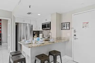 a kitchen with a counter with stools in it at Apartamento Moderno 2 Quartos The Enclave in Orlando