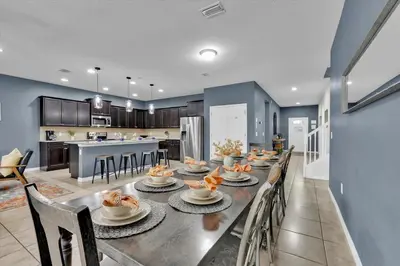 a dining room with a long table and a kitchen at Neverland Nook in Orlando