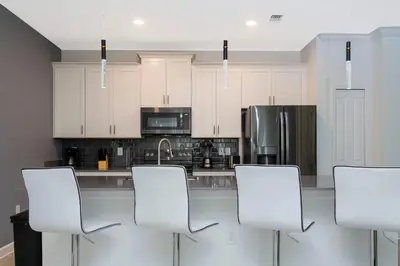 a kitchen with white cabinets and white chairs at Townhouse Moderna 4Q c/ Piscina /10 Min da Disney! in Kissimmee