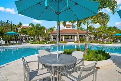 a table and chairs with an umbrella next to a pool at Moderno 3 Quartos no Vista Cay Resort in Orlando