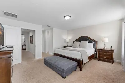 a bedroom with a bed and a ottoman in it at Vila 6 Quartos Storey Lake com Piscina & Spa in Kissimmee