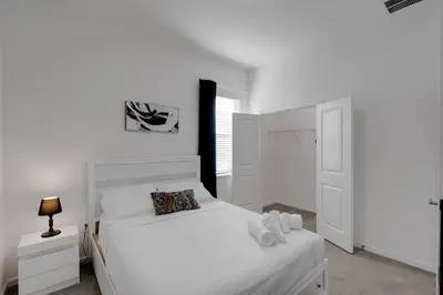 a white bedroom with a bed and a window at Cozy Rooms In An Elegant House in Kissimmee