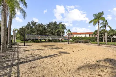 a volleyball court with palm trees and a building at Pool 4BR Resort Home Near Disney in Kissimmee