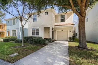 a white house with a tree and a driveway at Luxury Pool Home Near Disney Resort Amenities in Kissimmee