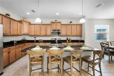 a kitchen with wooden cabinets and a table with chairs at Luxury Pool Home Near Disney Resort Amenities in Kissimmee