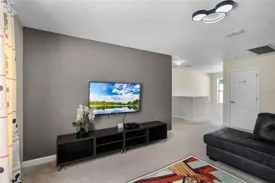 a living room with a flat screen tv on a wall at Luxury Pool Home Near Disney Resort Amenities in Kissimmee