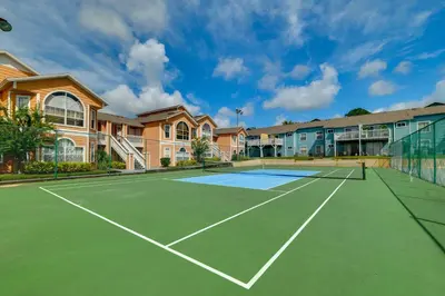 a tennis court in front of some houses at 5 Mi to WDW Resort-Style Condo with Pool Access in Kissimmee