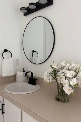 a bathroom sink with a vase of flowers and a mirror at Once upon a good stay - 7 Beds Pool Home by Disney in Kissimmee