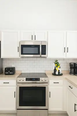 a kitchen with white cabinets and a microwave at Once upon a good stay - 7 Beds Pool Home by Disney in Kissimmee