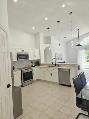 a kitchen with white cabinets and stainless steel appliances at Once upon a good stay - 7 Beds Pool Home by Disney in Kissimmee