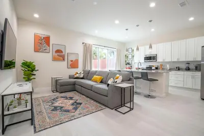 a living room with a couch and a kitchen at New Vacay Home 5BD 5BA - 5 miles to Disney in Orlando