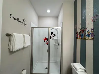 a bathroom with a shower with mickey mouse decals at 4BR-3BA Townhouse with Private Pool in Storey Lake in Kissimmee