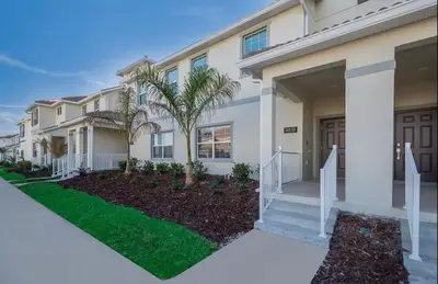 a house with palm trees in front of it at 4BR-3BA Townhouse with Private Pool in Storey Lake in Kissimmee