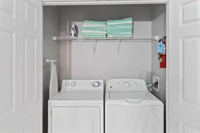 a small kitchen with a stove and towels on a shelf at Moderno apê 3 quartos no Vista Cay – Perto Disney in Orlando