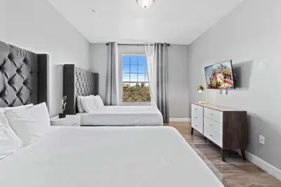 a white bedroom with two beds and a window at Moderno apê 3 quartos no Vista Cay – Perto Disney in Orlando