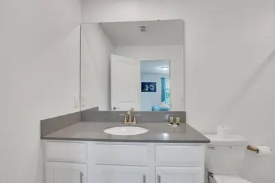 a white bathroom with a sink and a mirror at Last Minute Disney Private Pool Hot Tub Game Room Themed Bedrooms. Book Now SLR551 in Kissimmee