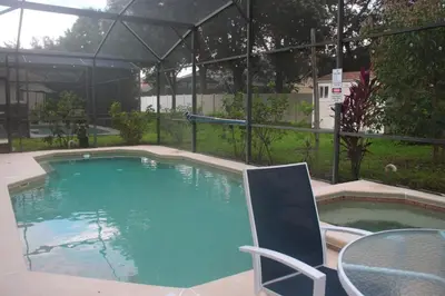a swimming pool with a chair and a table at Relaxing Villa near the Parks! in Orlando