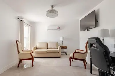 a living room with a couch and chairs and a tv at Paradise Apartment in Orlando